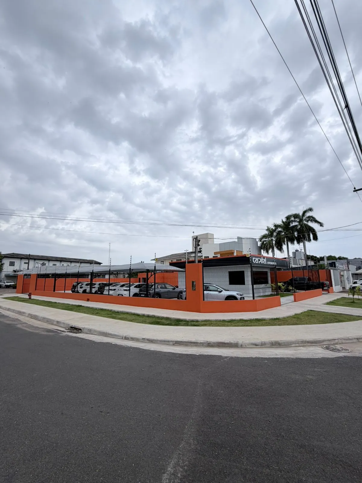 Terreno de esquina da Carpital Locadora, com muretas laranja e frota estacionada no pátio coberto
